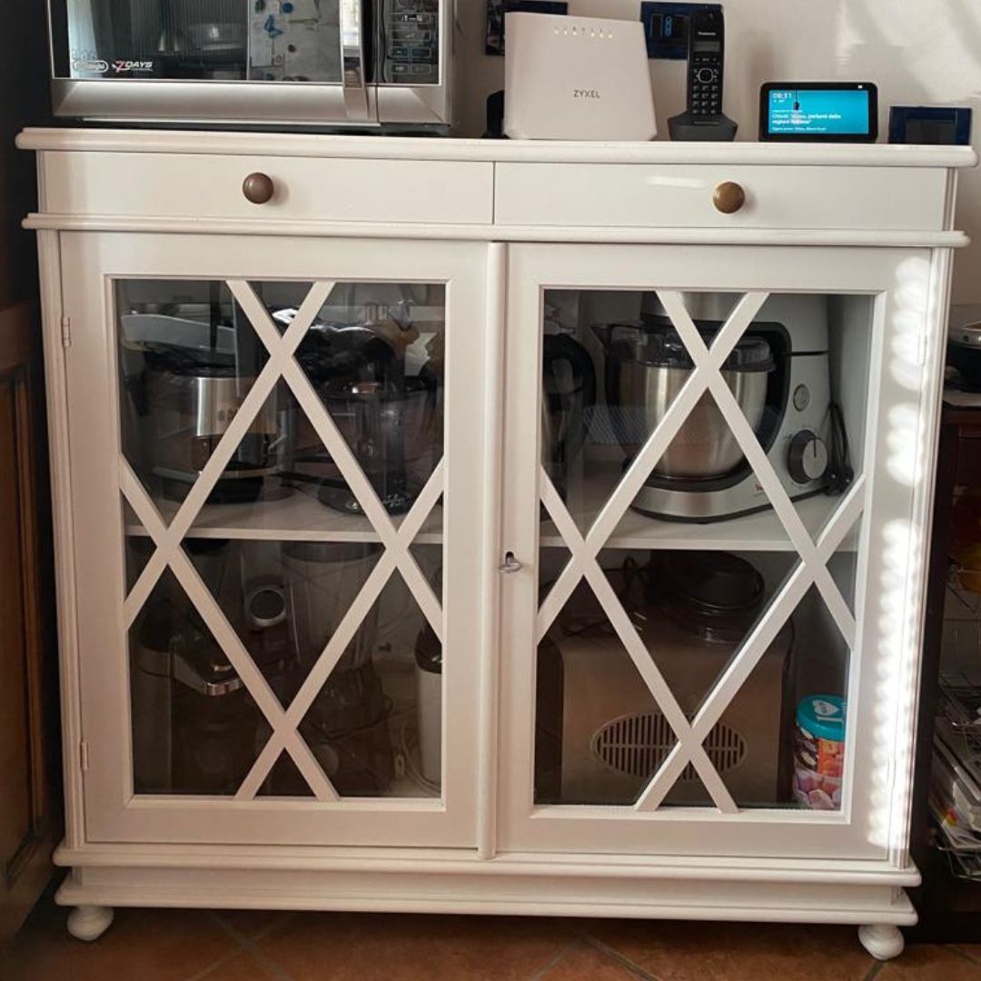 Libreria multifunzionale bianco opaco utilizzata come mobile dispensa in cucina, con ante a vetro.